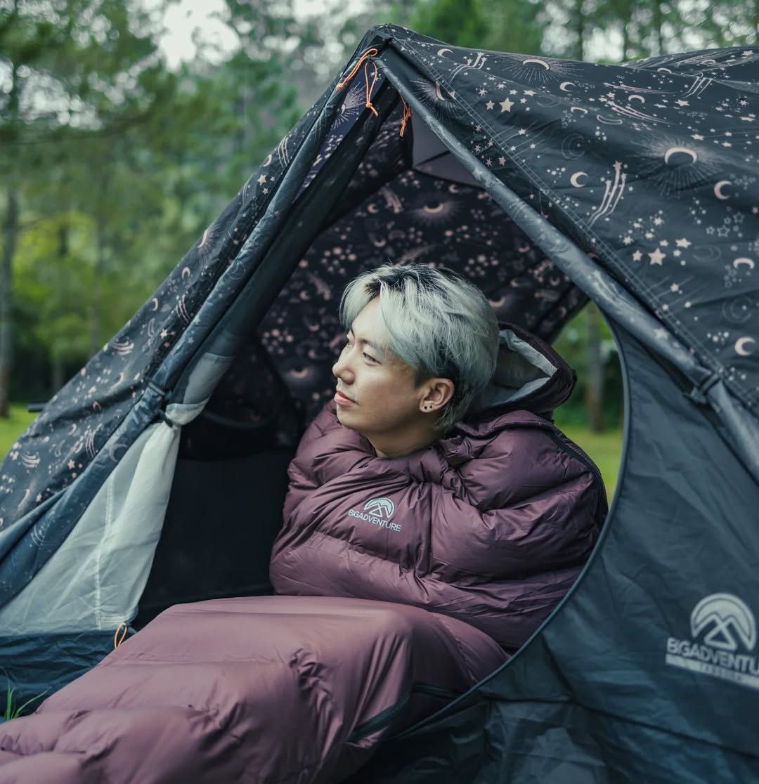 Sleeping bag warna orange yang digulung di atas batu besar